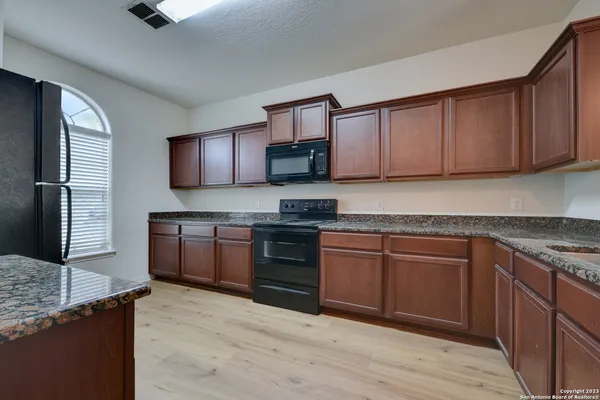 a kitchen with granite countertop wooden cabinets a stove top oven and granite counter tops