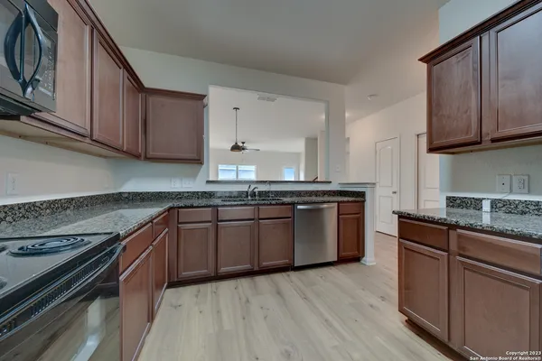 a kitchen with granite countertop wooden cabinets and a stove top oven