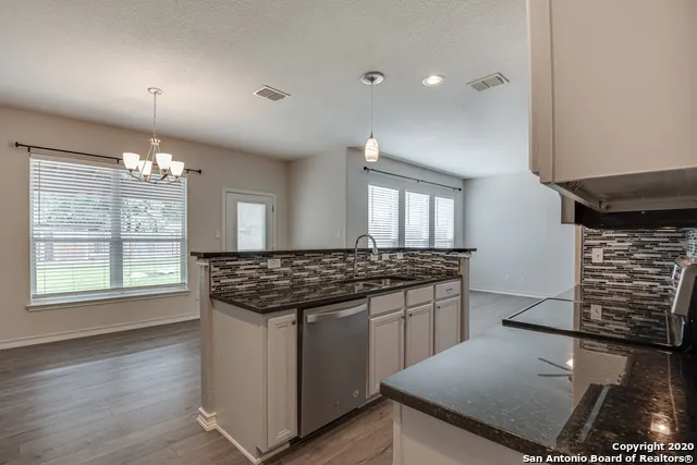 a kitchen with granite countertop a sink cabinets and stainless steel appliances