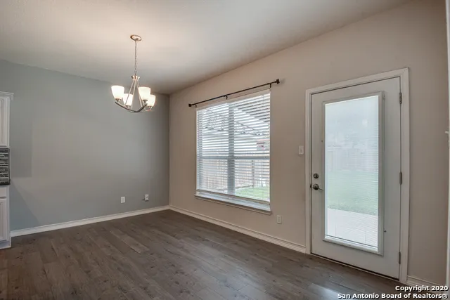 a view of a kitchen with a refrigerator kitchen island wooden floors wooden cabinets and a counter top space