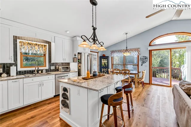 a open kitchen with stainless steel appliances granite countertop a stove a refrigerator a sink dishwasher with a dining table and chairs with wooden floor