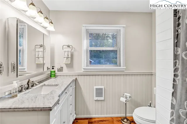 a bathroom with a granite countertop sink mirror vanity and toilet
