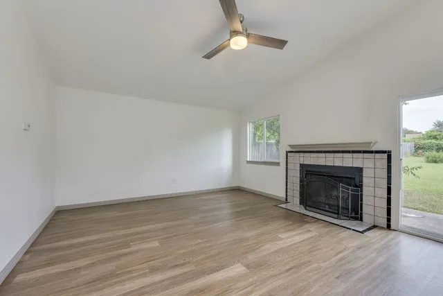 an empty room with wooden floor fireplace cabinet and windows
