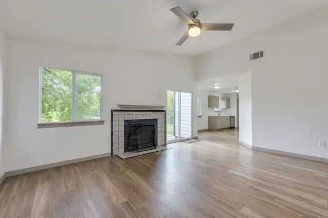 a view of empty room with wooden floor fireplace and a window