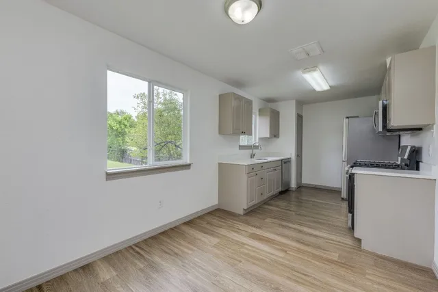 a large white kitchen with a sink a window and stainless steel appliances