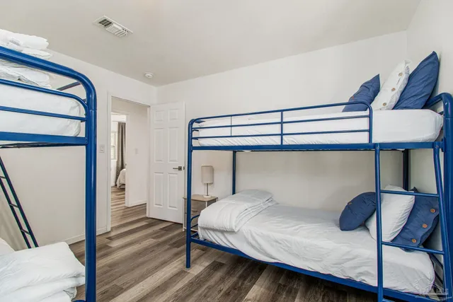 a bedroom with a bed a lamp and wooden floor