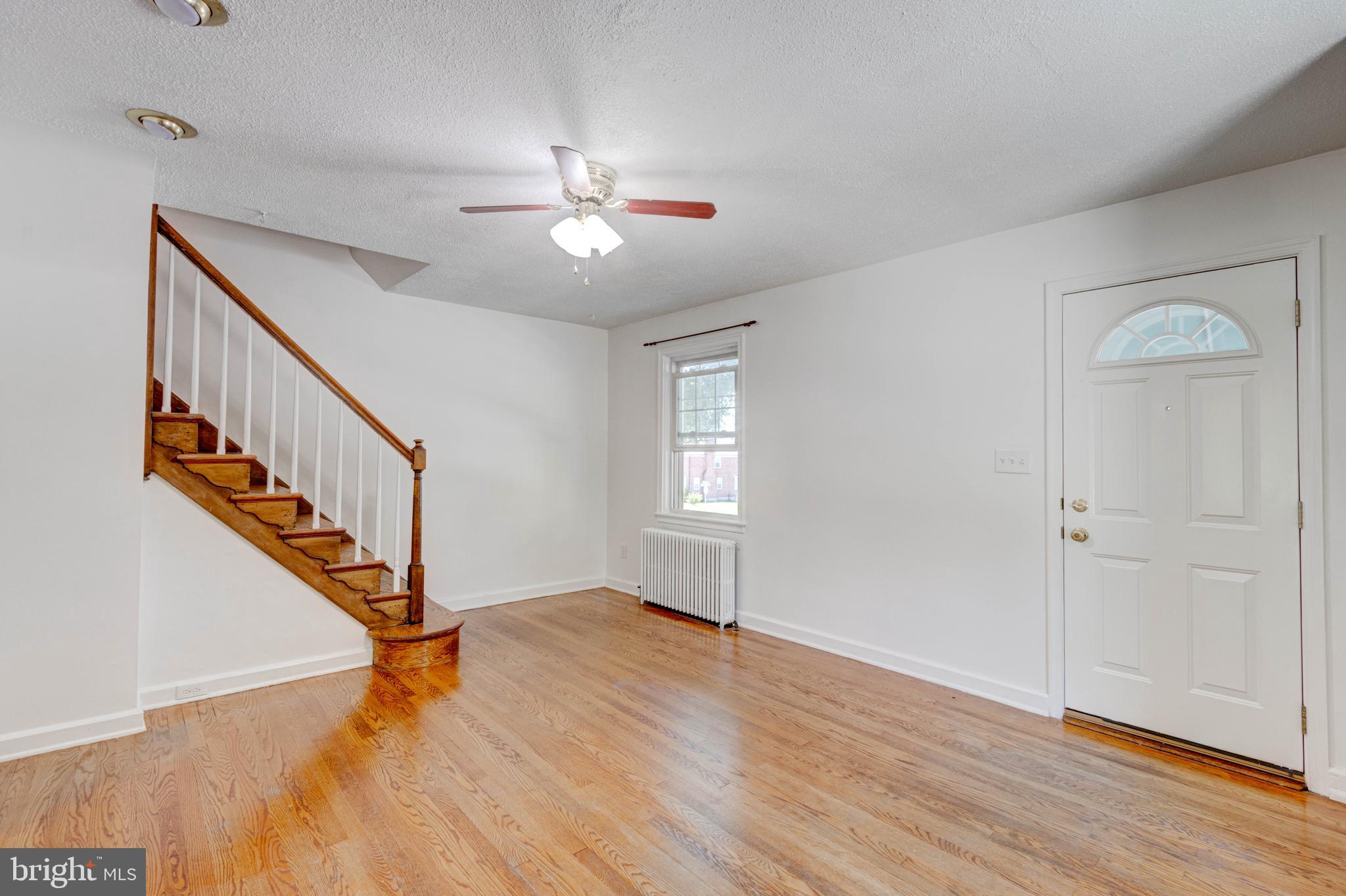 523 Academy Road Catonsville, MD 21228 - Photo 2 of 26 a view of an empty room with wooden floor and fan