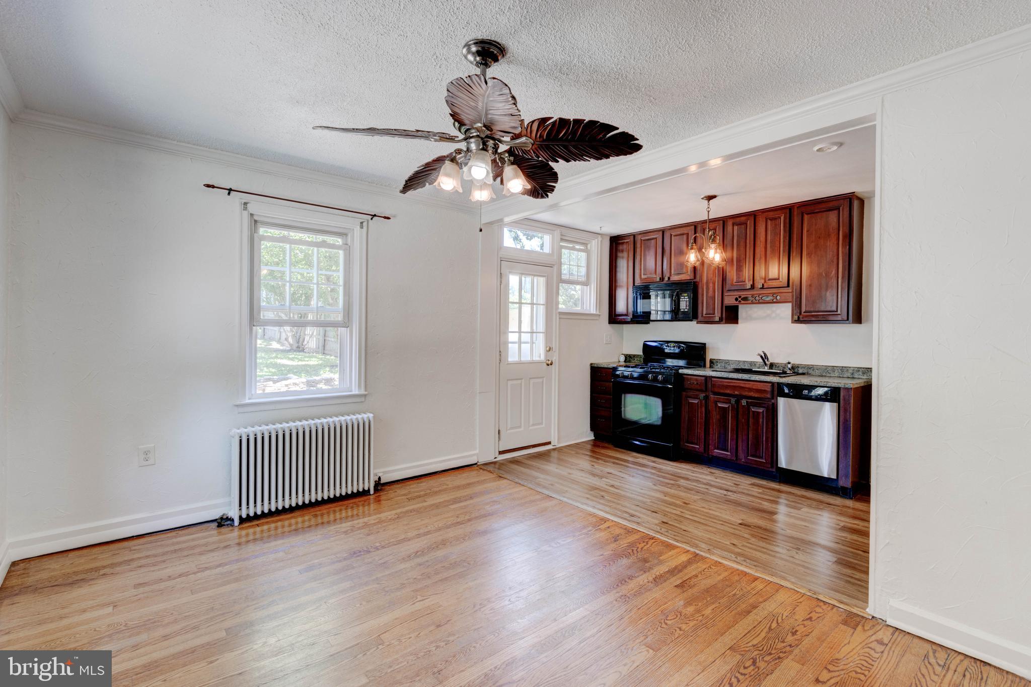 523 Academy Road Catonsville, MD 21228 - Photo 6 of 26 a kitchen with stainless steel appliances granite countertop a stove top oven a refrigerator a chimney and a wooden floor