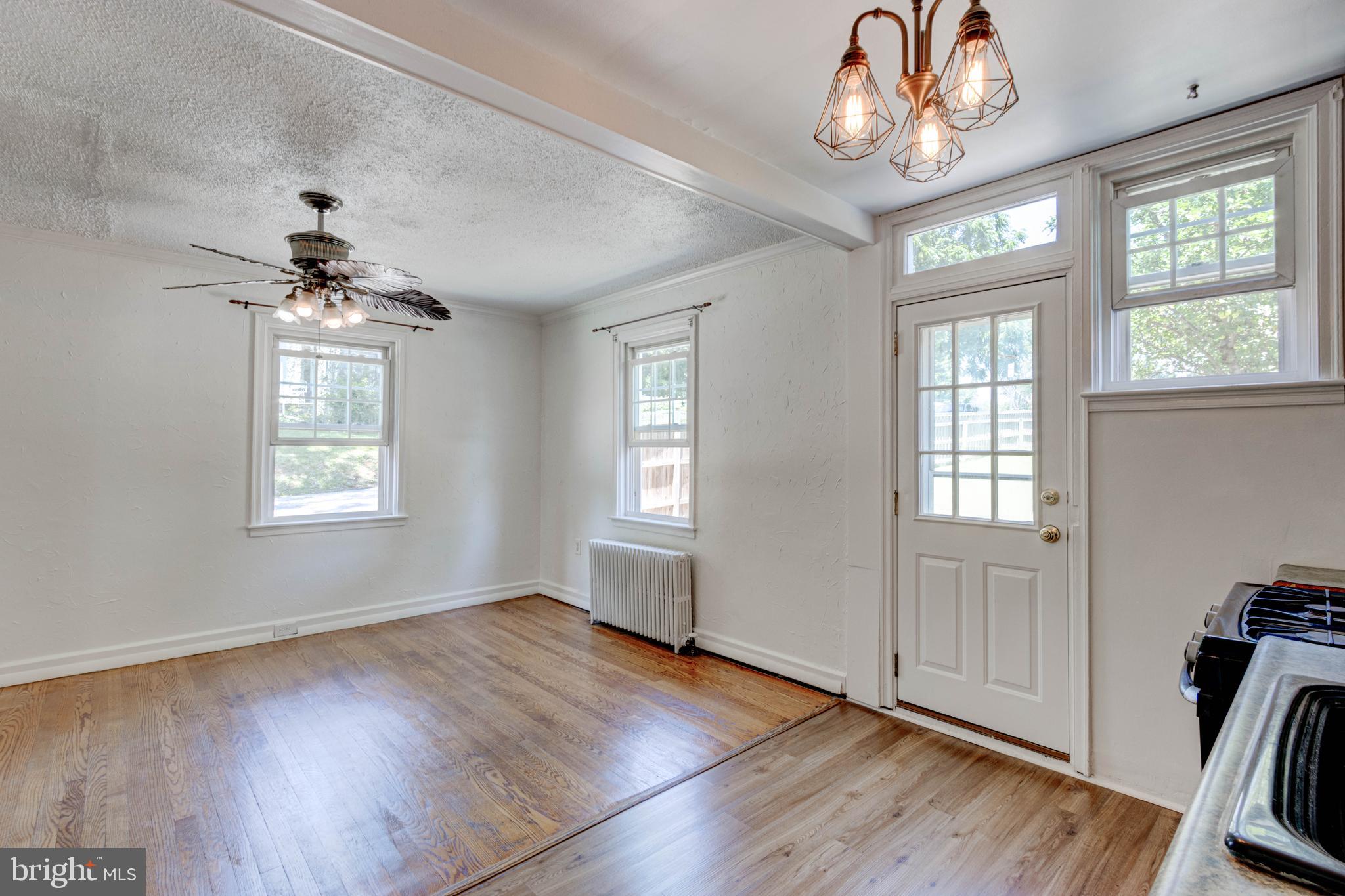 523 Academy Road Catonsville, MD 21228 - Photo 9 of 26 an empty room with wooden floor chandelier and windows