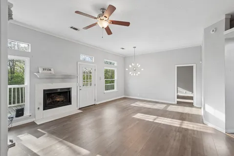 an empty room with windows fireplace and a kitchen view
