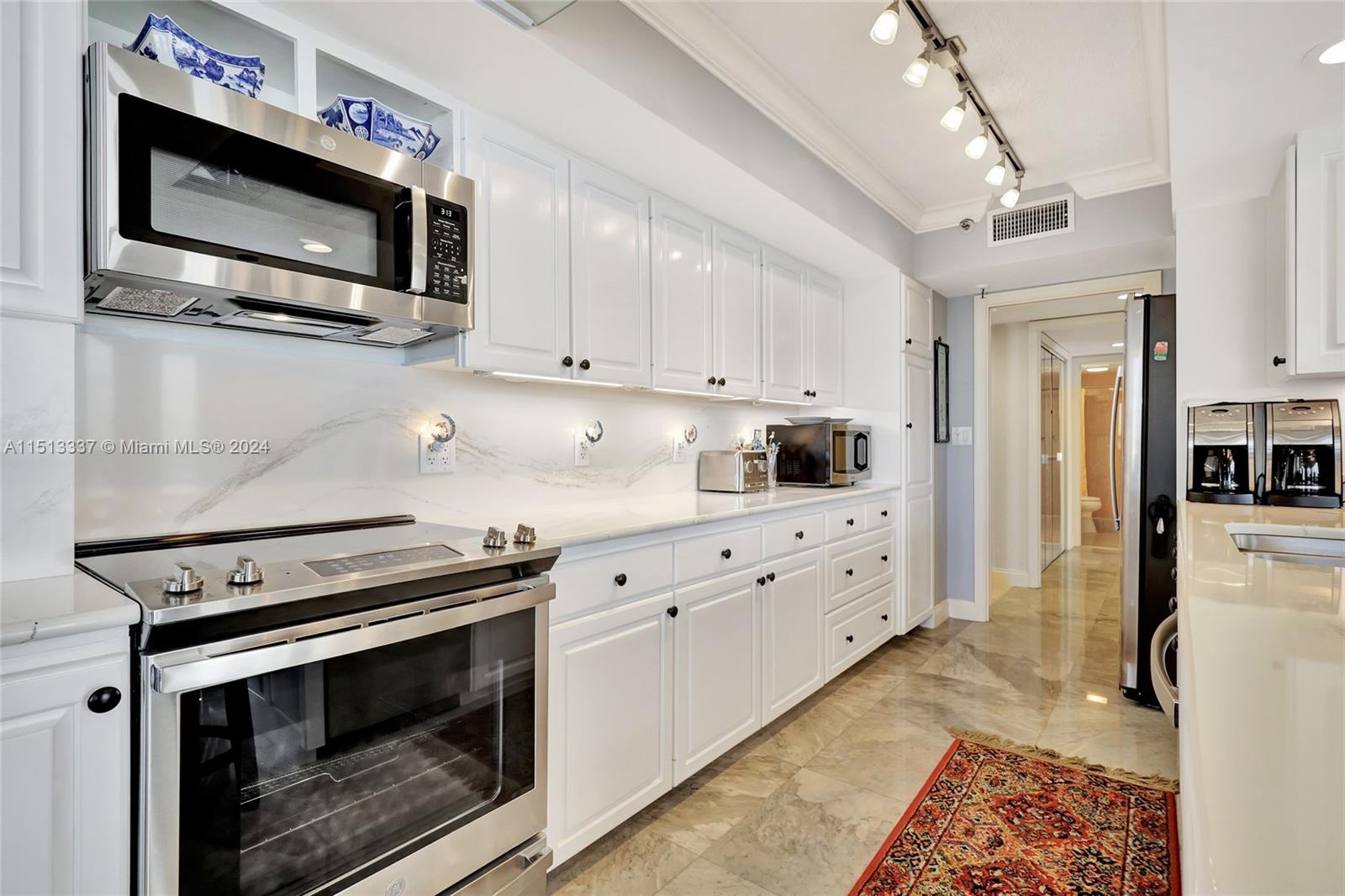 5380 North Ocean Drive, Unit 22J Riviera Beach, FL 33404 - Photo 30 of 83 a kitchen with stainless steel appliances white cabinets a stove a sink and a microwave