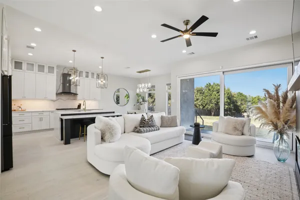 a living room with furniture kitchen view and a large window