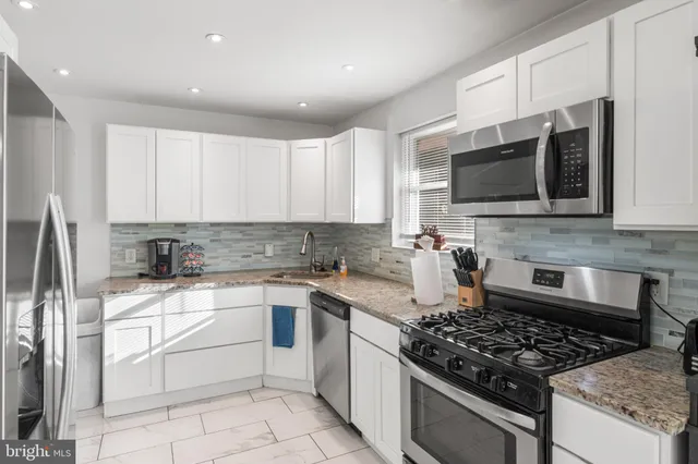 a kitchen with stainless steel appliances granite countertop a stove top oven a sink dishwasher and a refrigerator