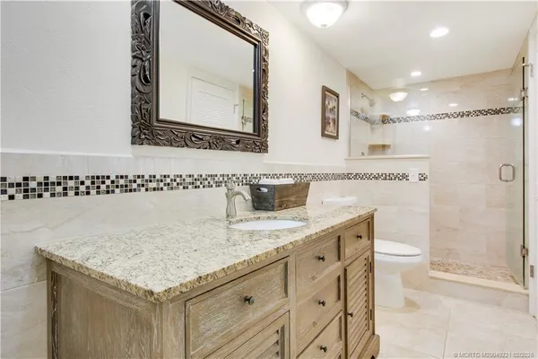 a bathroom with a granite countertop sink a toilet and a mirror