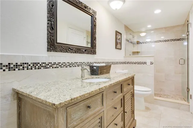 a bathroom with a granite countertop sink a toilet and a mirror