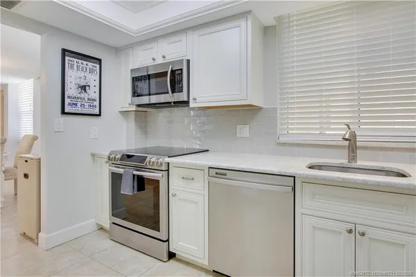 a kitchen with granite countertop white cabinets and stainless steel appliances