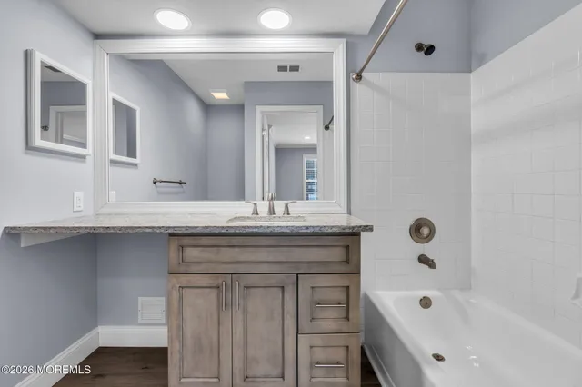 a bathroom with a granite countertop sink mirror and a bath tub