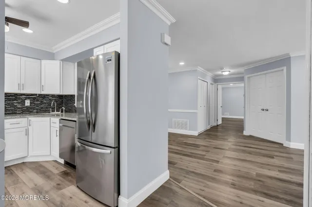 a view of kitchen refrigerator and white cabinets