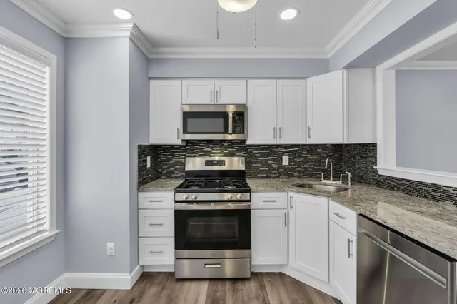 a kitchen with cabinets stainless steel appliances a sink and a stove