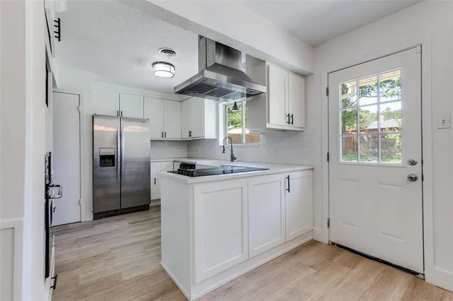 a kitchen with stainless steel appliances granite countertop a refrigerator a sink dishwasher a stove and white countertops with wooden floor