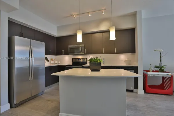a kitchen with kitchen island a counter top space a sink stainless steel appliances and cabinets