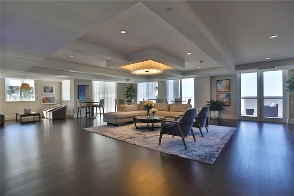 a living room with couches and a dining table with wooden floor