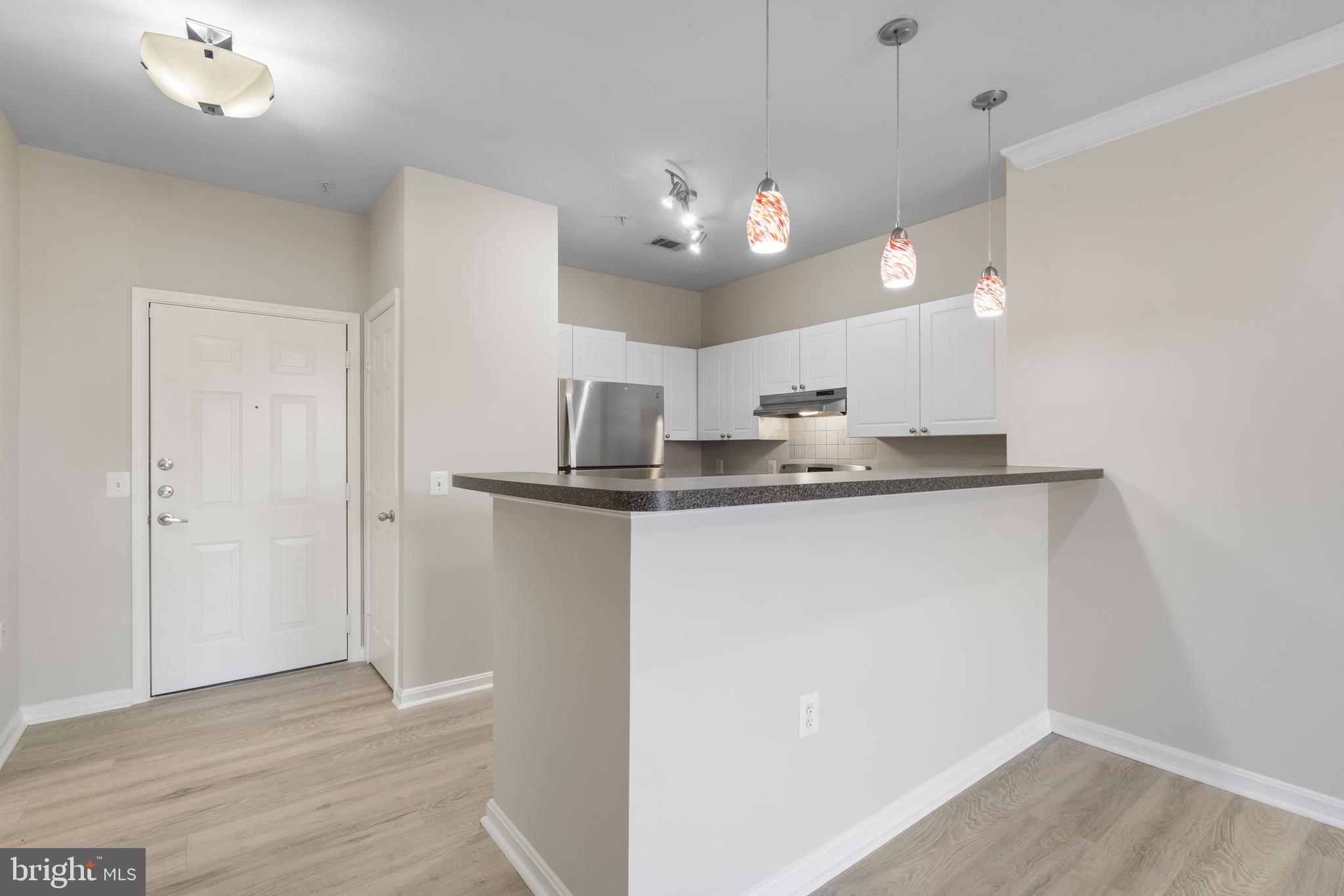 3851 Aristotle Court, Unit 1402 Fairfax, VA 22030 - Photo 12 of 31 an empty room with wooden floor and kitchen view