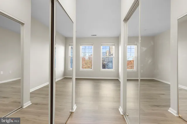 a view of an empty room with window and wooden floor