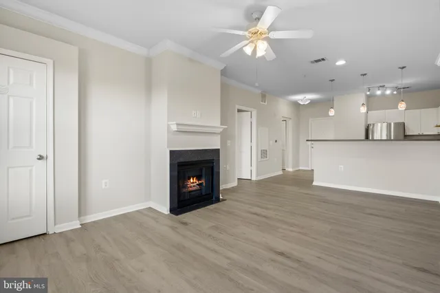 a view of an empty room with wooden floor a fireplace and a window