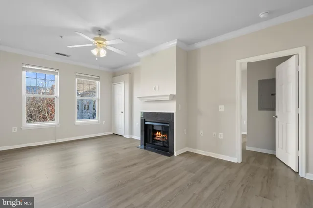 a view of an empty room with wooden floor fireplace and a window