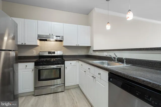 a kitchen with granite countertop a stove sink and cabinets