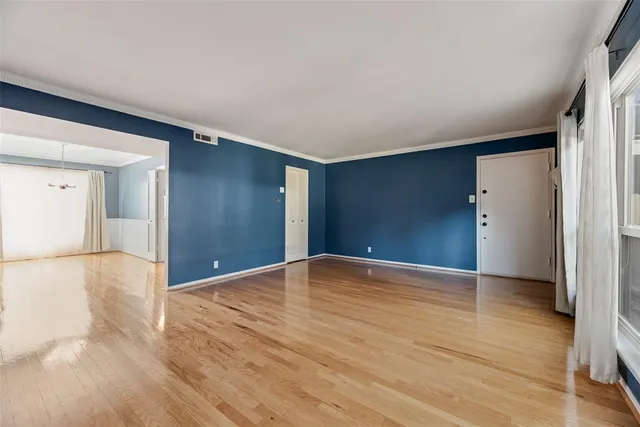 a view of an empty room with wooden floor and closet