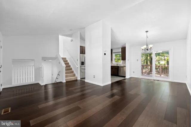 an empty room with wooden floor staircase and windows