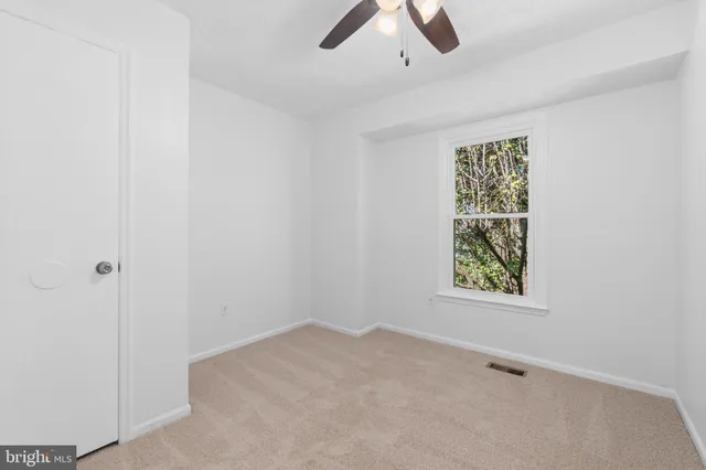 an empty room with ceiling fan and window
