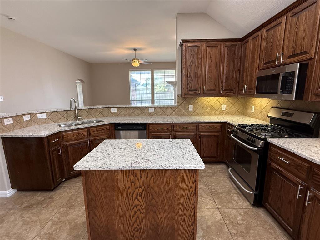 108 Cole Street Forney, TX 75126 - Photo 15 of 39 a kitchen with granite countertop stainless steel appliances and wooden cabinets