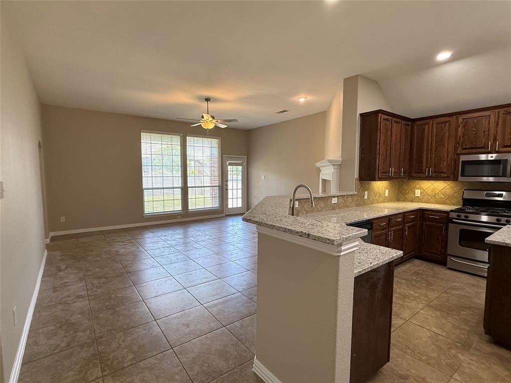 108 Cole Street Forney, TX 75126 - Photo 4 of 39 a kitchen with kitchen island granite countertop a stove sink and cabinets