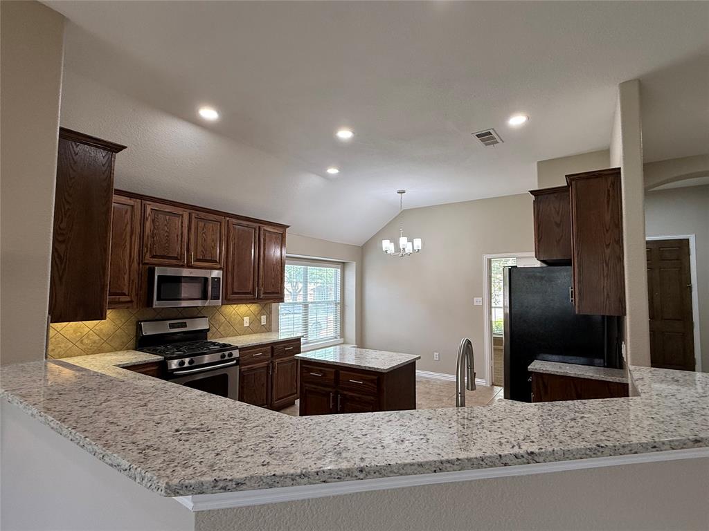 108 Cole Street Forney, TX 75126 - Photo 9 of 39 a kitchen with stainless steel appliances granite countertop a stove a sink and a refrigerator