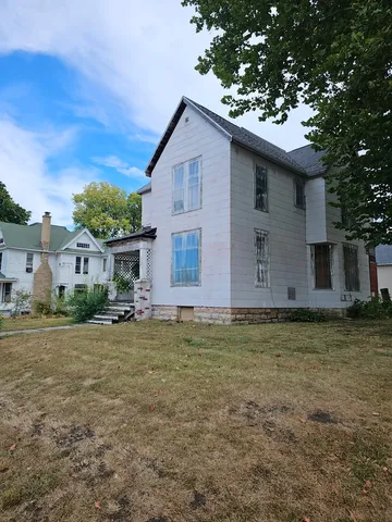 a front view of house with yard and trees in the background