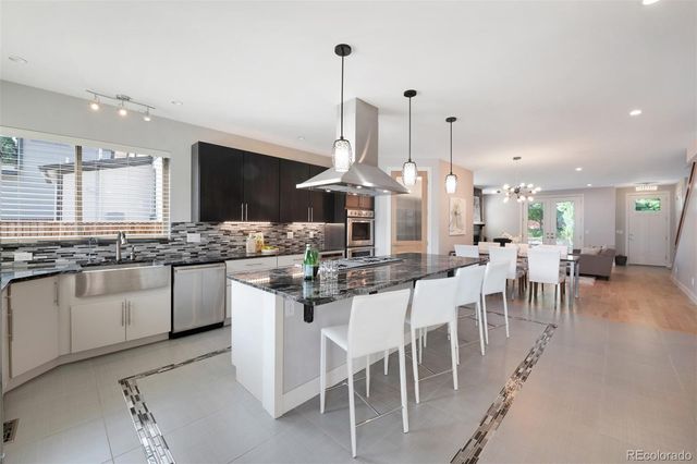 a kitchen with stainless steel appliances kitchen island granite countertop a table chairs sink and cabinets
