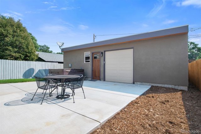 a patio with a table and chairs and potted plants