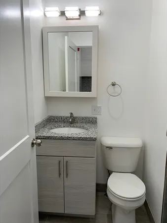 a bathroom with a granite countertop toilet sink and mirror