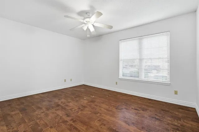 an empty room with a chandelier fan and windows