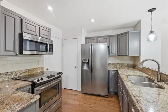 a kitchen with granite countertop a sink stove and refrigerator