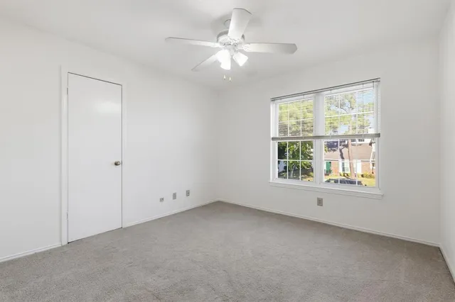 an empty room with chandelier fan and windows