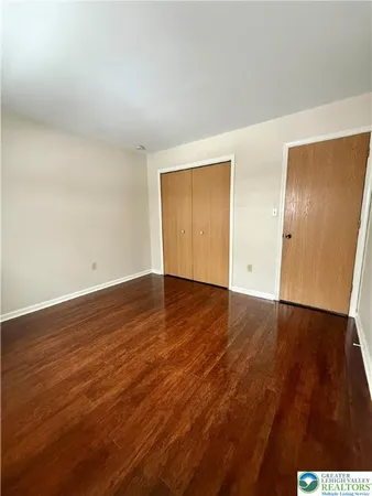 a view of an empty room with wooden floor and closet
