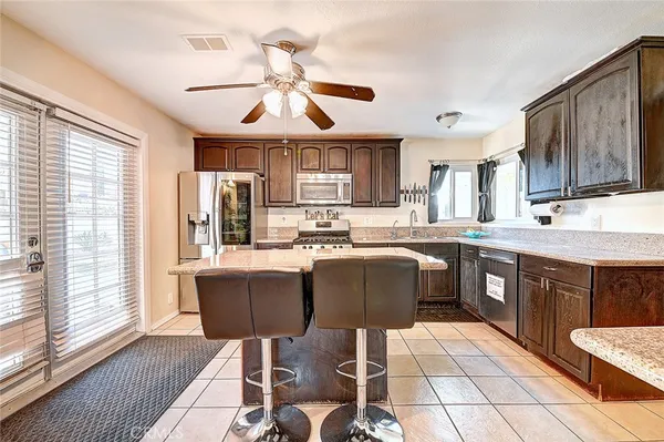 a kitchen with stainless steel appliances granite countertop a sink a stove a refrigerator cabinets and a dining table with wooden floor