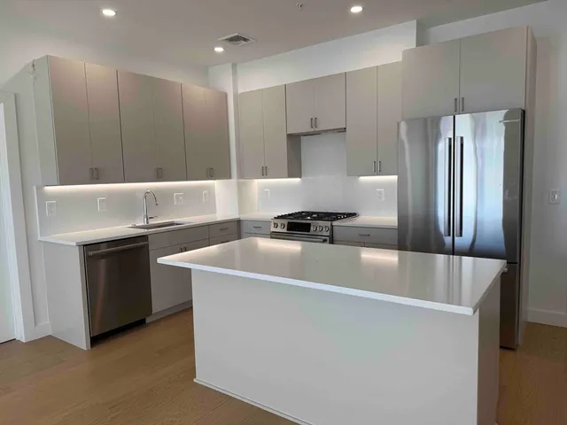 a kitchen with kitchen island stainless steel appliances a sink stove and refrigerator