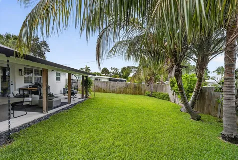 a view of a backyard with couches under an umbrella