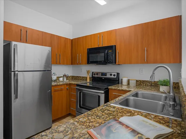 a kitchen with stainless steel appliances granite countertop a refrigerator stove top oven a sink and dishwasher