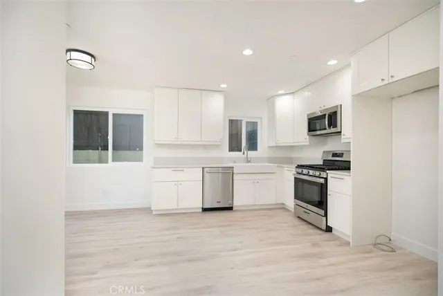 a kitchen with granite countertop a refrigerator stove top oven and sink